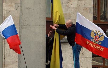 Proruský aktivista odstrauje ukrajinskou vlajku.