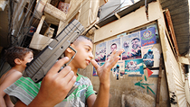 Palestinští chlapci si hrají na válku proti Izraeli pod plakátky oslavujícími přední teroristy. Palestinští chlapci si hrají na válku proti Izraeli pod plakátky oslavujícími přední teroristy.