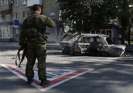 Ukrajinský separatista pozoruje vrak auta po bombardování vládními silami