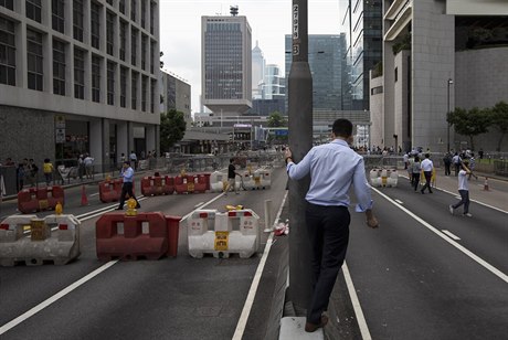 Byznysmen ve finanní tvrti Hongkongu sledují pouliní zátarasy, vztyené...