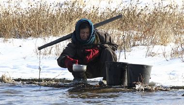 Na jin stran eky. Severokorejka nabr ledovou vodu z eky Yalu (Ja-lu),...