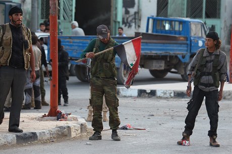 Ozbrojenec z al-kaidistické Fronty an-Nusra s roztrhanou syrskou vlajkou.