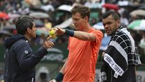 Tom Berdych (uprosted) si stuje u rozhodho v zpase s Jo-Wilfriedem...