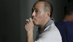 A man smokes a cigarette outside an office building in Beijing