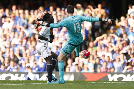 Thibault Courtois fauluje v pokutovém území Bafetimbiho Gomise ze Swansea, za...