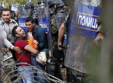 Migrant s díttem v náruí uvízl mezi kordonem policist a davem uprchlík....