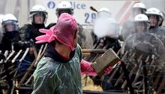 Demonstrant hází po policii dlaky z chodníku.