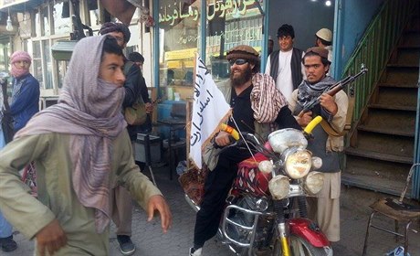 Bojovnk Talibanu na motocyklu s vlajkou radiklnho hnut ve mst Kunduz.