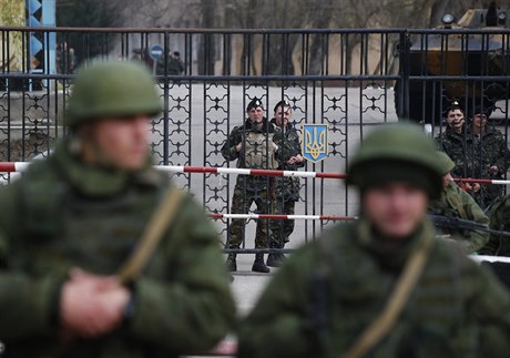 Ukrajintí vojáci za branou kerské základny, v popedí ruské jednotky.