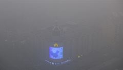 Reklamní tabule záí ve smogem, zahaleném Pekingu.