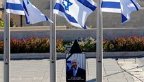 Portrt imona Perese pod izraelskmi vlajkami na Knesetskm nmst.