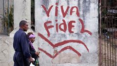 Lidé procházejí kolem grafiti. A ije Fidel