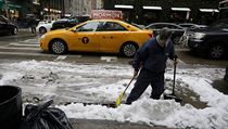 A man sweeps the street after snow fell in Manhattan, New York City