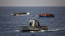 Loď libyjské pobřežní stráže míjí dva gumové čluny plné uprchlíků. | na serveru Lidovky.cz | aktuální zprávy