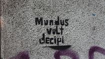 Stencil s první částí latinského výroku, který zní celý Mundus vult decipi,... Stencil s první částí latinského výroku, který zní celý Mundus vult decipi,...
