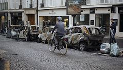 Cyklista projídí kolem torz nkolika ohoelých aut v centru Paíe.