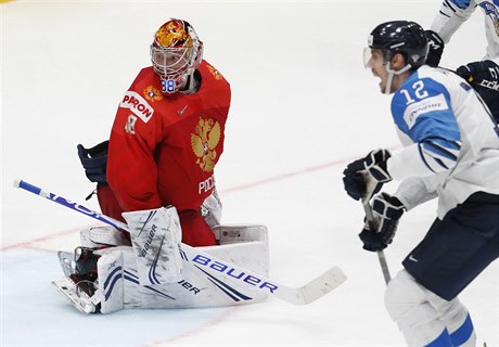 Ruský branká Andrej Vasilevskij okovan hledí za sebe, zatímco stelec gólu...