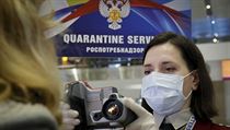 Zaměstnankyně letiště Pulkovo měří teplotu cestující.