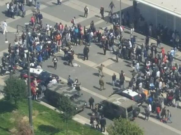 Zde je vid�t  kruh asi sta lid�, p�ev�n� africk�ch imigrant�, kte�� tr�v� sv� dny na n�m�st�  Duca d'Aosta a v jeho  st�edu je n�kolik voj�k� a policist�.