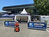 Informační a pomocné stanoviště pro postižené, v pozadí střed hlavní tribuny s Uvítacím centrem