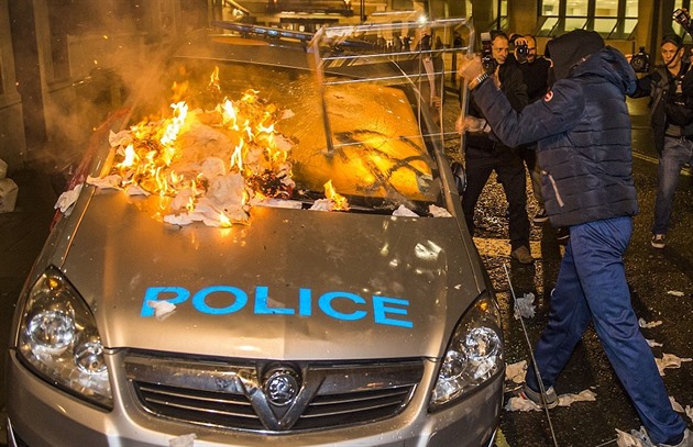 Antikapitalista v hodinkách a bund znaky Colmar zapaluje policejní auto....