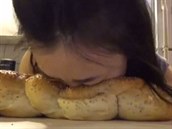 Dívka se natáí, jak buí hlavou do rzných druh chleba.
