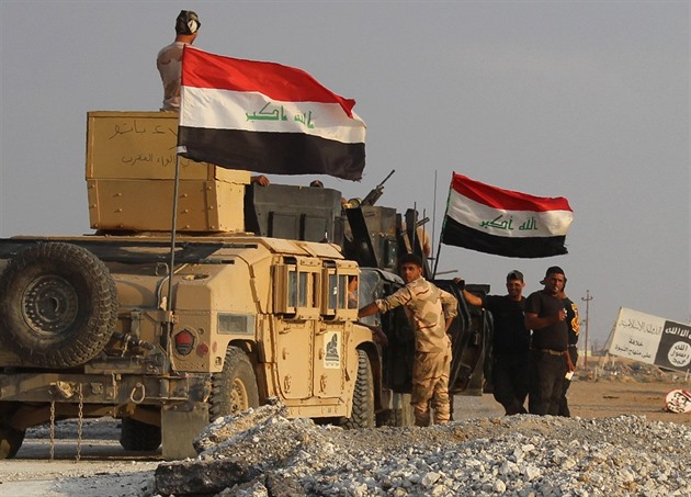 Irátí vojáci se shromádili u billboardu, který patí Islámskému státu.