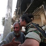 Dojatého staříka líbá kurdská bojovnice.