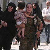 Kurdská bojovnice nese v náručí malou holčičku.