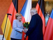 Merkelová k poesení ruky dostala i kytici.