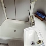 V koupelně je k dispozici umyvadlo, sprcha a praktický úložný prostor