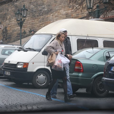 Zatmco Veronika nese tkou taku, jej ochrnce jde s rukama v kapse.