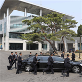 Kimova delegace se slavnou ochrankou mužů kteří běží podél jedoucí limuzíny.
