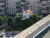 Parkourista Pavel Kashin práv provádí salto vzad na okraji stechy. Po dopadu...