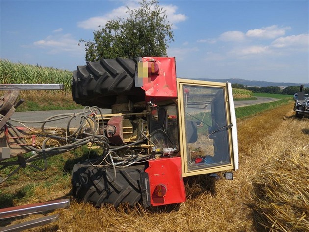 Traktor skonil po nehod u umvaldu pevrácený mimo silnici.