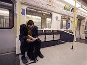 A man wears a mask as he reads on a tube in London, Monday, March 16, 2020. For...