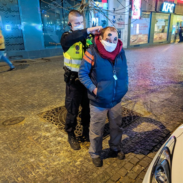 Policista nasazuje bezdomovci rouku.