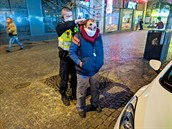 Policista nasazuje bezdomovci rouku.