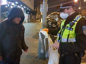 Policisté rozdávají rouky bezdomovcm.