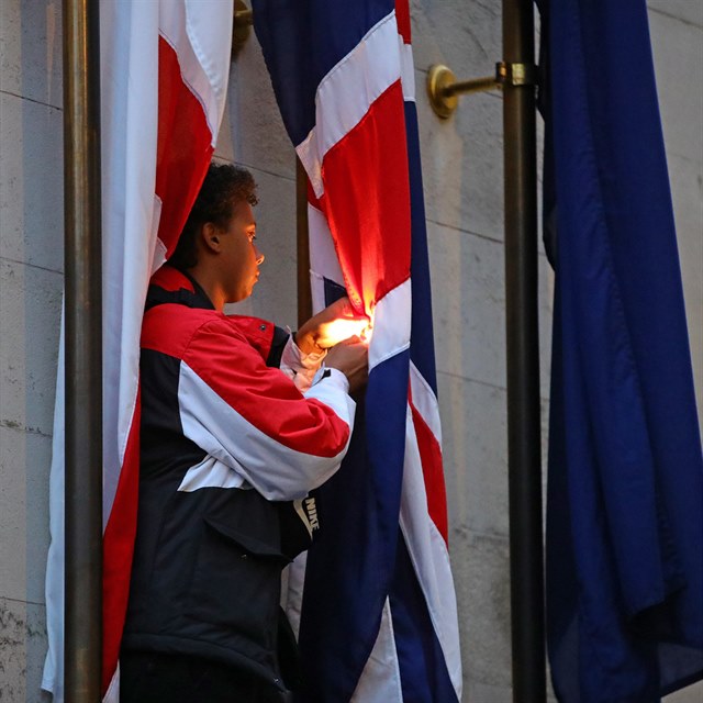 Demonstrant se sna zaplit britskou vlajku.