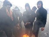 Nohy si migranti ohívají nad ohnm.