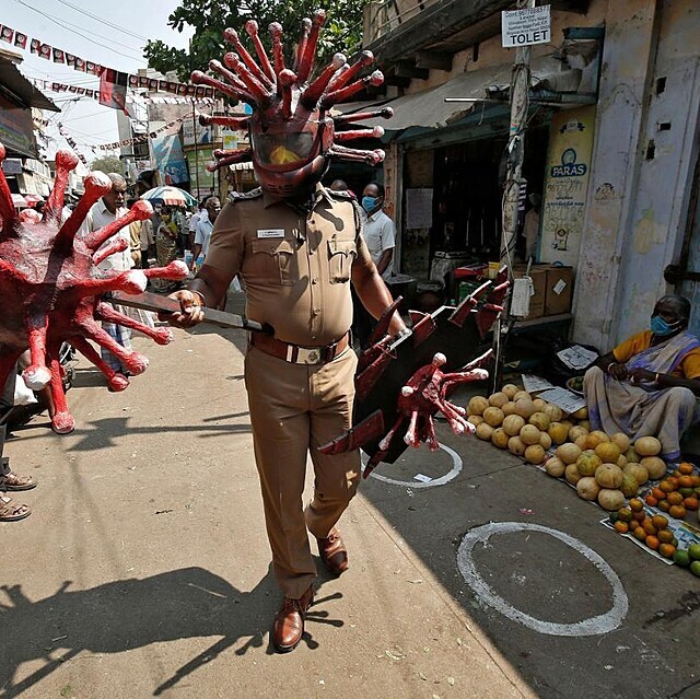 Policista vysvětluje Indům, jaká opatření mají dodržovat jako prevenci přenosu...