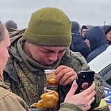Mladý válečný pije čaj a jí paštiku, zatímco mu ukrajinská  žena vytáčí v...