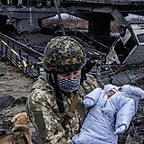 Ukrajinský voják zachraňuje batole z trosek zcela vybombardovaného města Ilpin.
