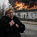 Zhroužena žena před hořícím domem.