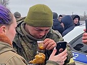 Mladý válený pije aj a jí patiku, zatímco mu ukrajinská  ena vytáí v...