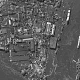 Satelitní snímek ukazuje zaplavenou domy v obytnou oblasti v blízkosti přehrady.