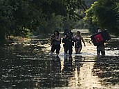 Místní obyvatelé s kufry opustili své domovy a brodí se zaplavenou vodou poté,...