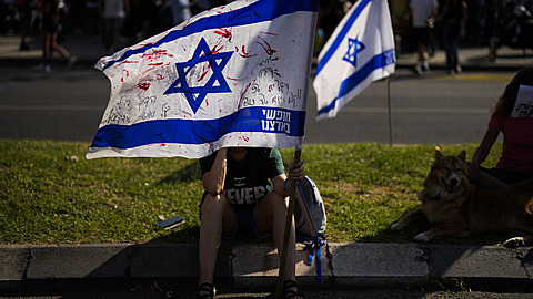 Žena drží  izraelskou vlajku popsanou červenou barvou během protestu, v němž se...