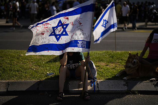 ena drí  izraelskou vlajku popsanou ervenou barvou bhem protestu, v nm se...